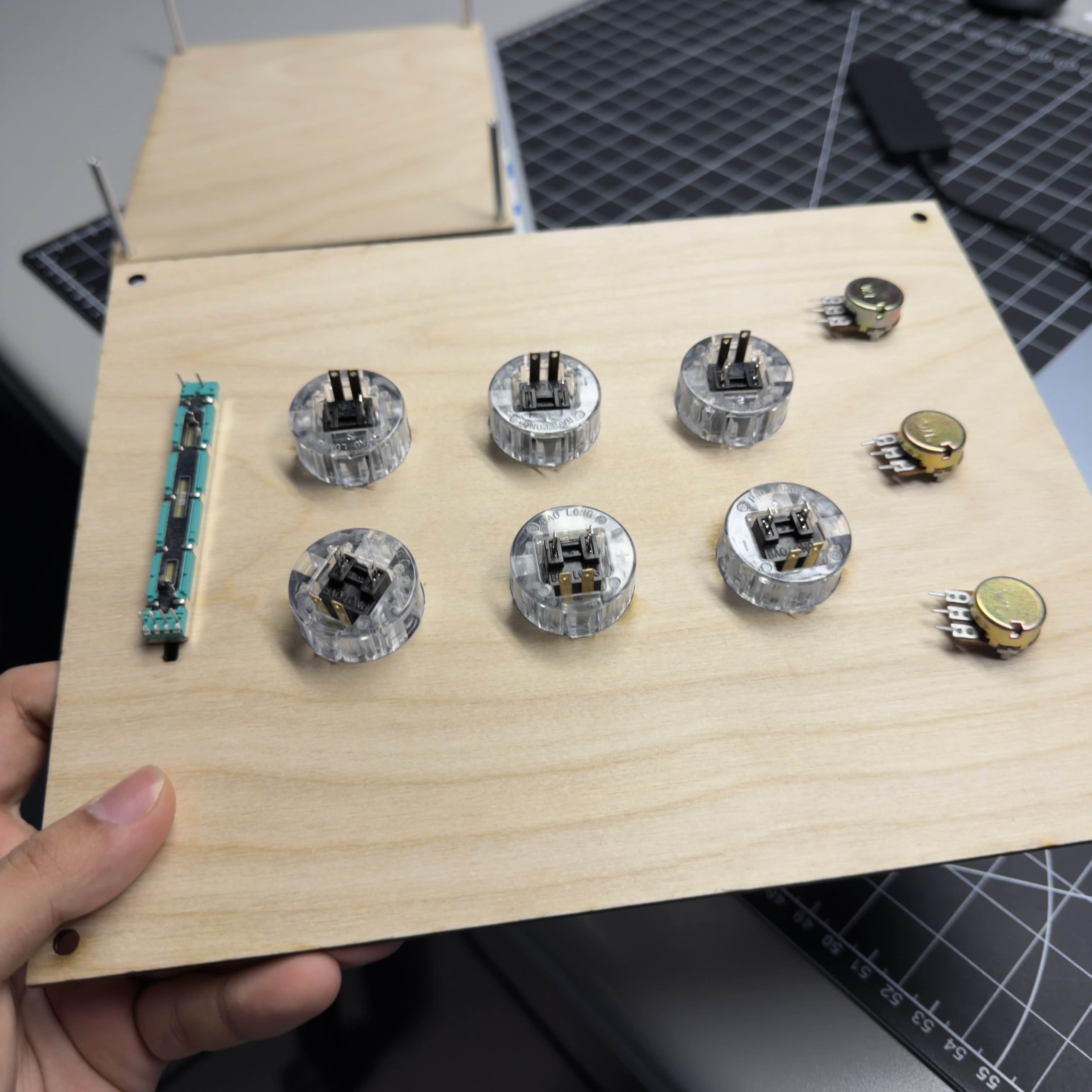 Initial hardware layout test on the wooden panel. I checked fit and spacing for buttons, potentiometers, and the slider before making permanent wiring connections.